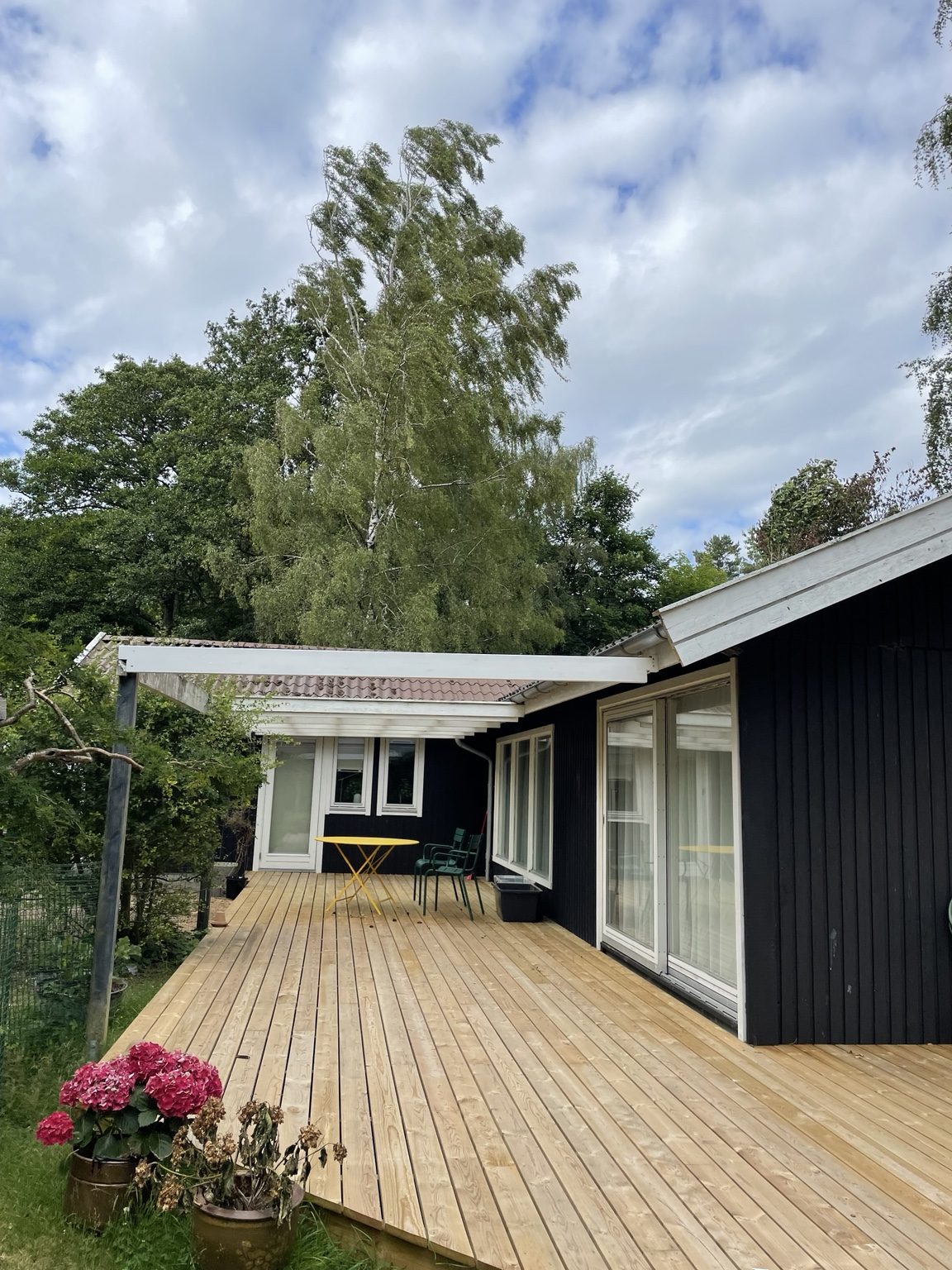 Lang træterrasse ved sort hus